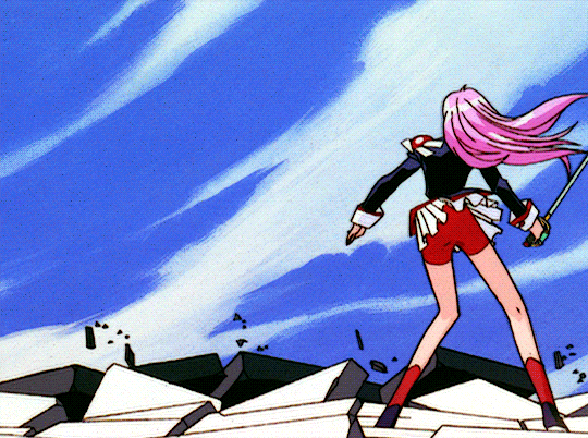 Utena GIF. She is tall and has long pink hair, light skin, and blue eyes. She is dressed in a black military-style uniform with red shorts and tasseled shoulder pads. She wields a large silver sword.